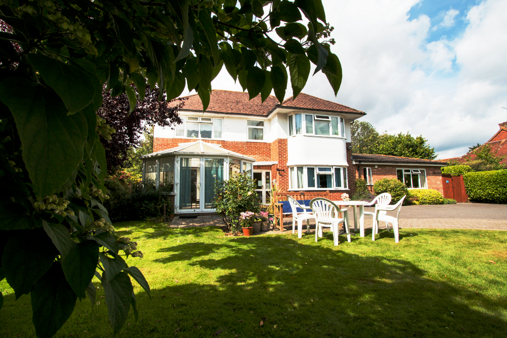 Bright and sunny garden with conservatory and tables and chairs where residents can enjoy the sunshine
