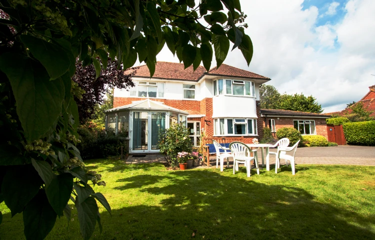 Bright and sunny garden with conservatory and tables and chairs where residents can enjoy the sunshine