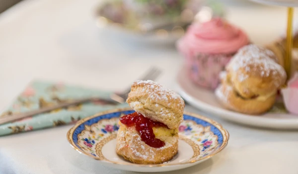 Jam and cream scone on a plate with afternoon in the background