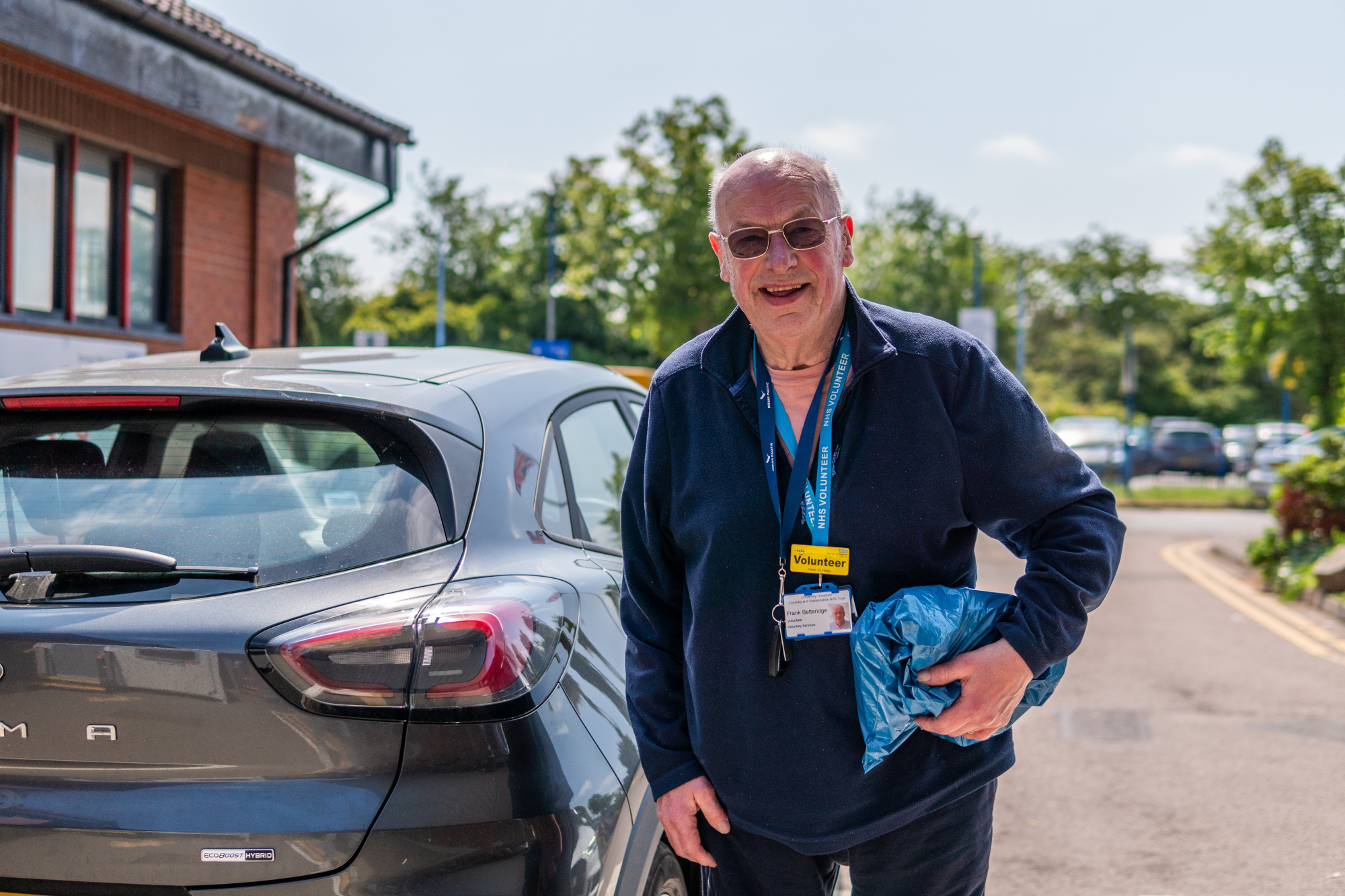 Older Volunteer Man Standing By Car
