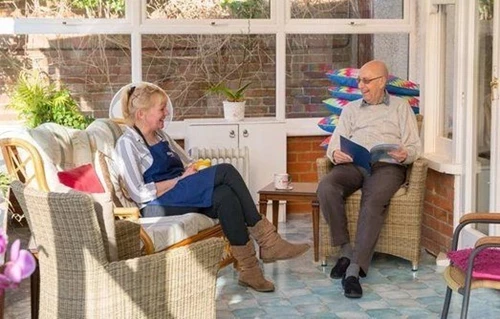 Resident and staff member sitting together reading