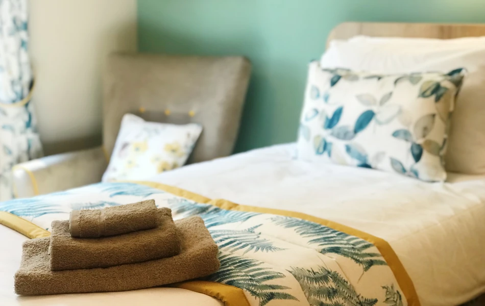 A beautifully styled resident room at Westall House dementia care home in Horsted Keynes with fresh towels and decorative pillows