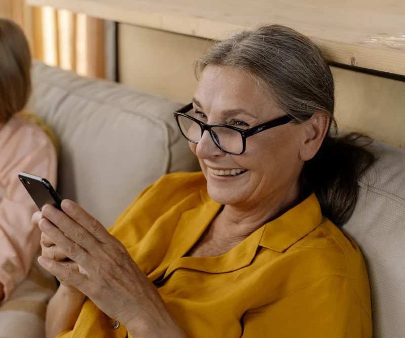 Older Woman Smiling Whilst Looking At Phone