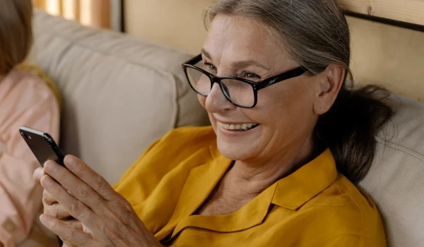 Older Woman Smiling Whilst Looking At Phone