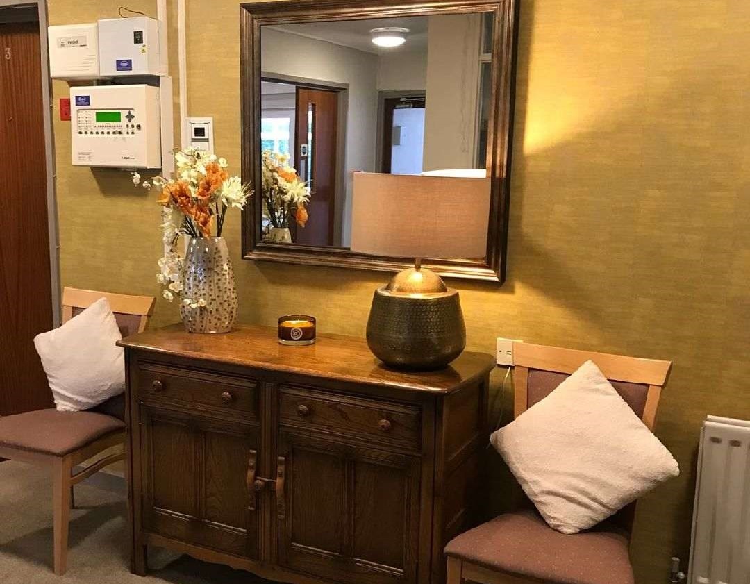 A desk and chairs in the entrance with a lamp