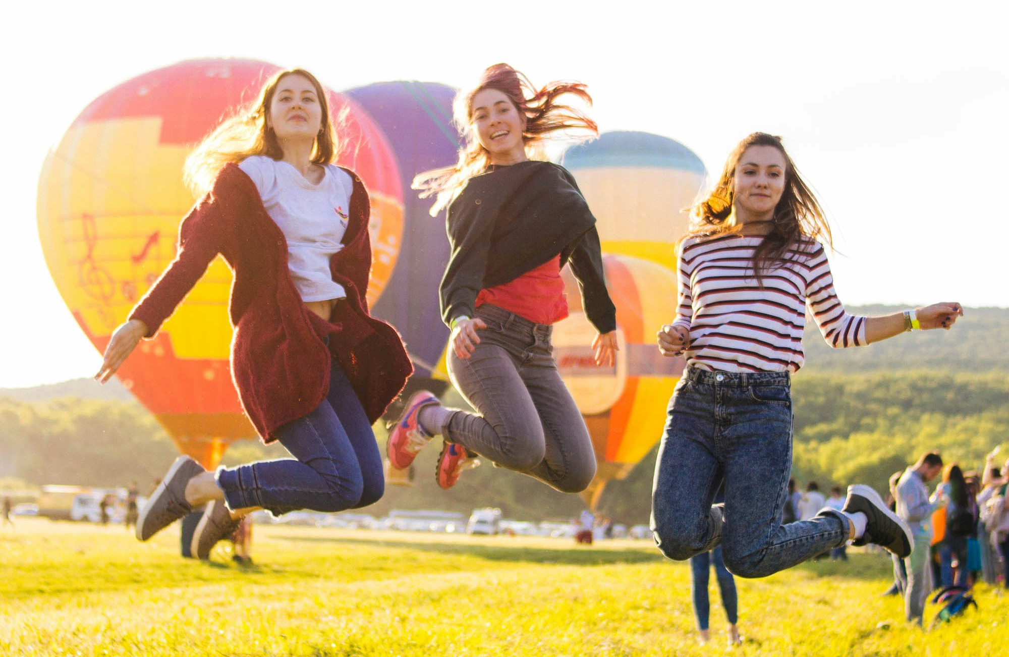 Group Of Women Jumping In Front Of Hot Air Balloons