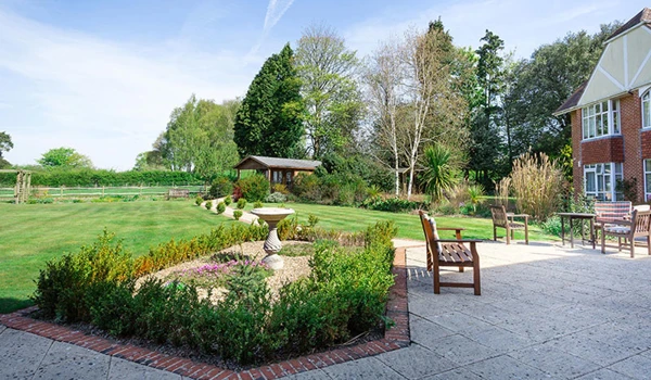 Beautiful expansive garden at Westall House, with paved patio and seating area and a variety of plants and trees