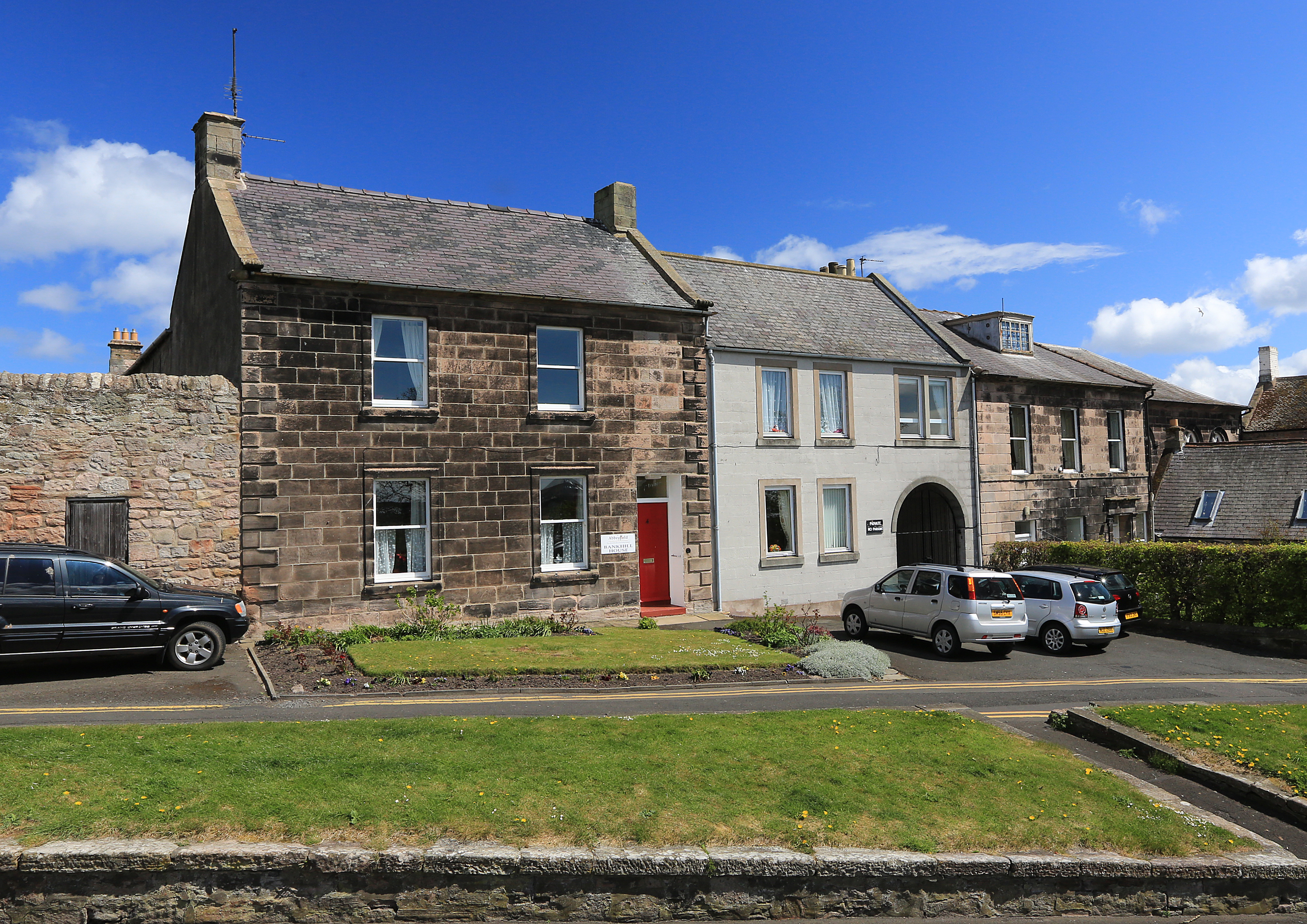 The front of a small stone house with grassed areas outside