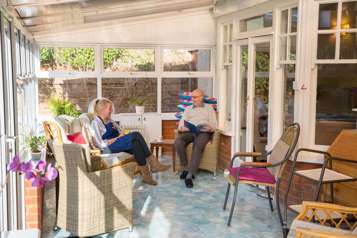 Resident and staff member at Lade House enjoying a chat in the conservatory