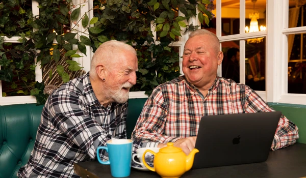 Two Happy Older Men Looking At A Laptop Together