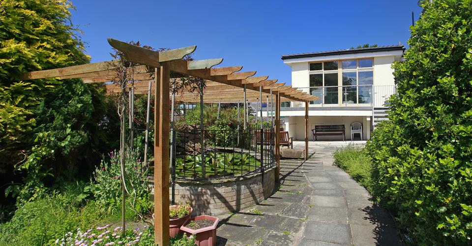 A raised pond under a pergola in the garden at Lear House