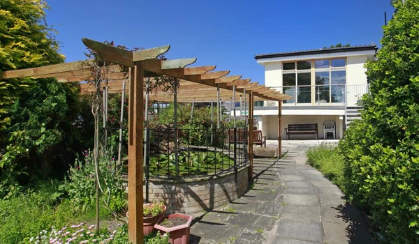 A raised pond under a pergola in the garden at Lear House