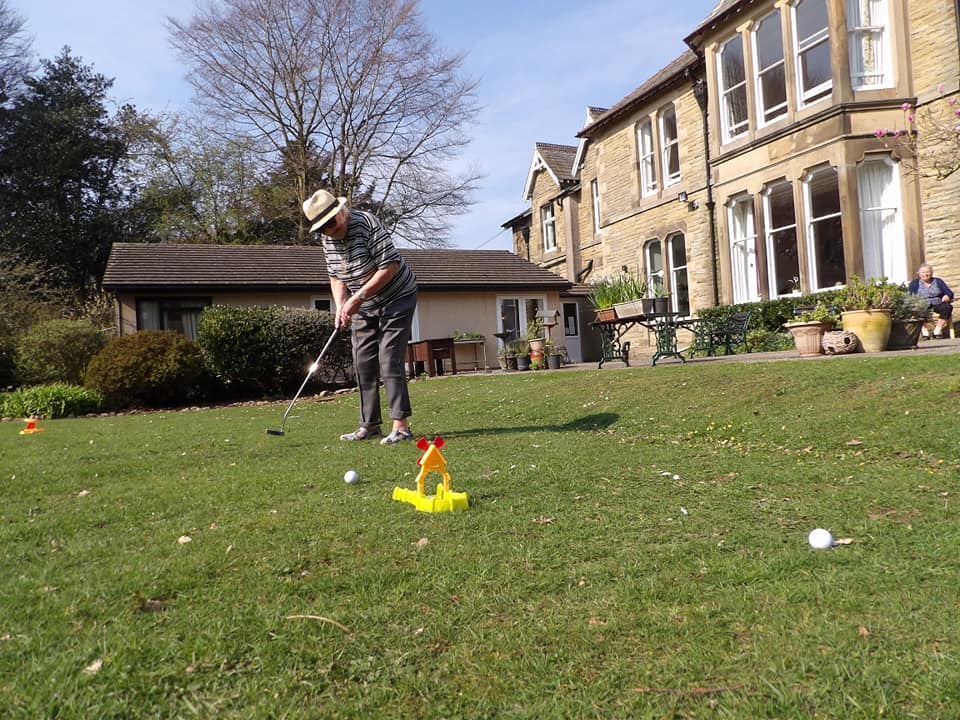 A resident playing golf in the garden at Cove House