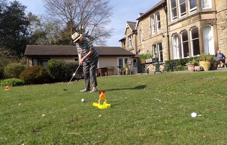 A resident playing golf in the garden at Cove House
