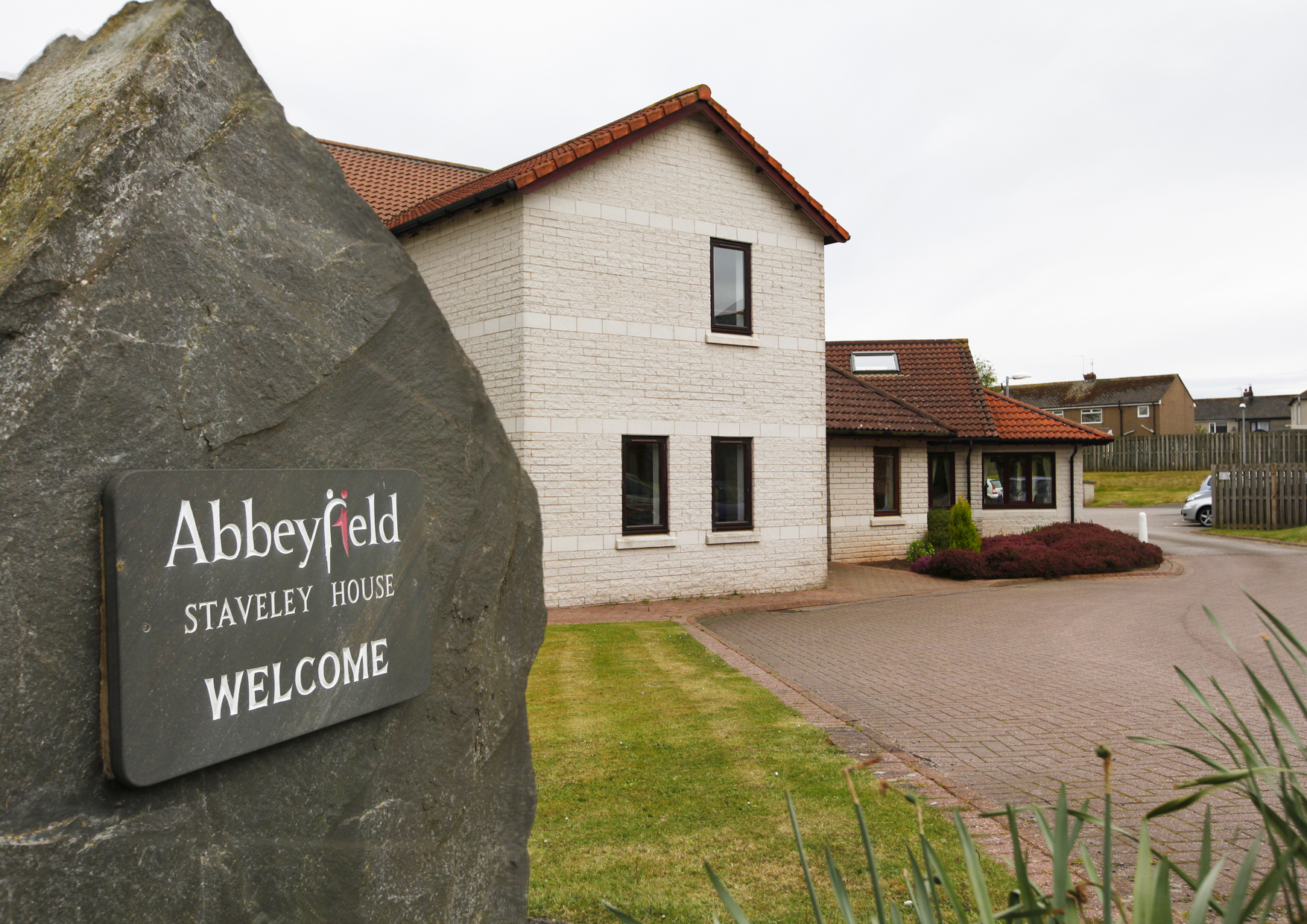 Abbeyfield welcome sign on a stone outside the house
