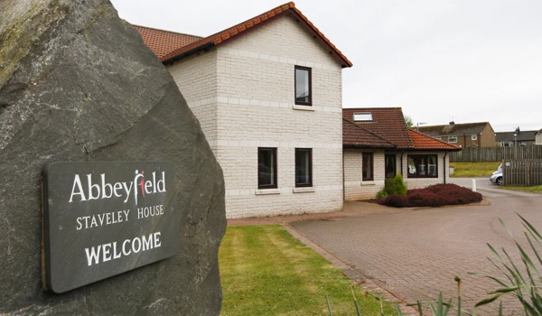 Abbeyfield welcome sign on a stone outside the house