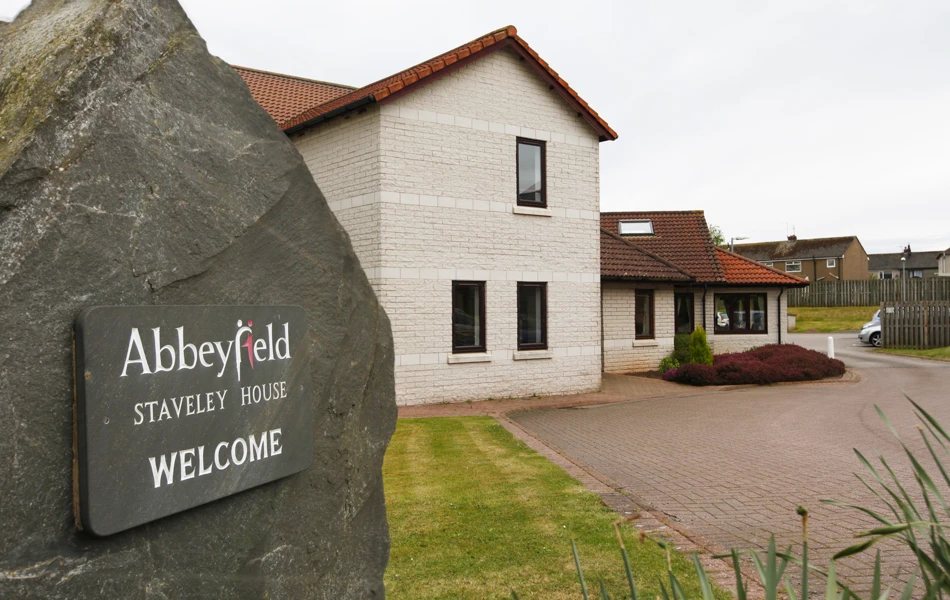 Abbeyfield welcome sign on a stone outside the house