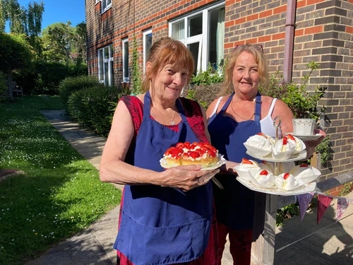 Two staff members holding strawberry cakes outside