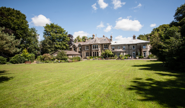 A huge garden with large trees and Cove House in the distance