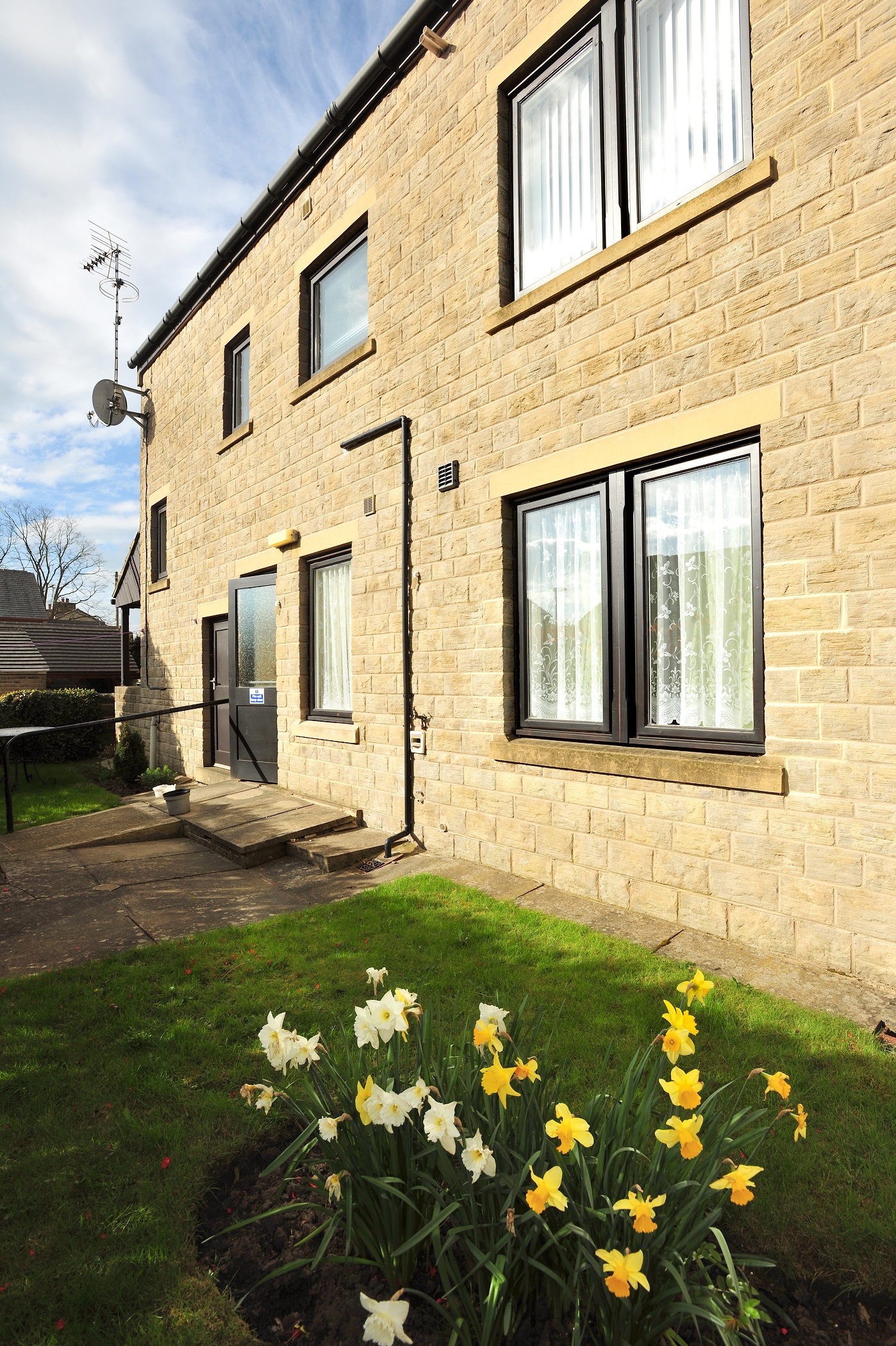 A view of Abbeyfield House set behind a bed of daffodils