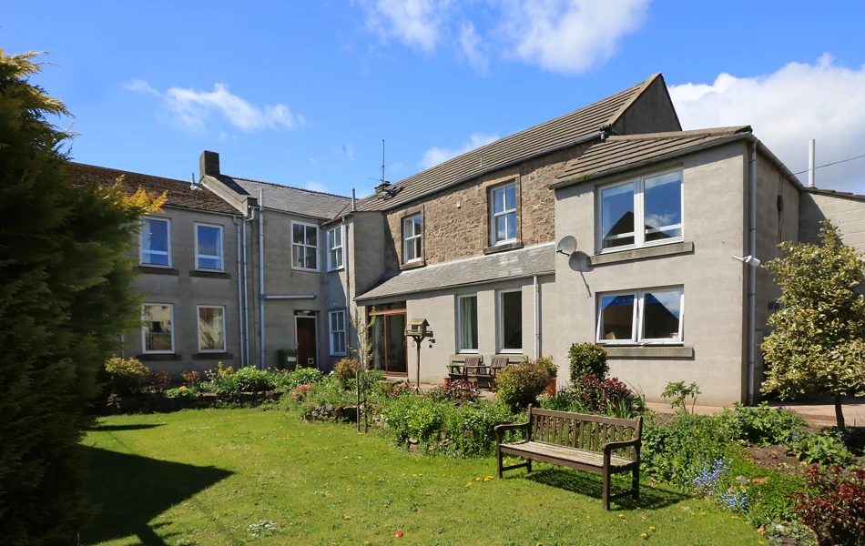A bright garden to the rear of the house with a park bench