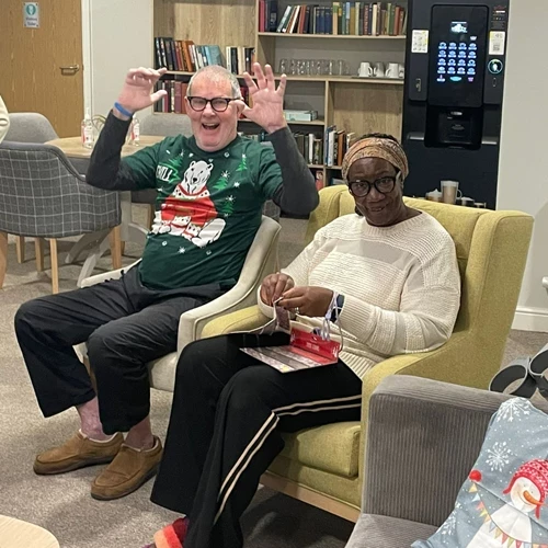 2 residents sitting down with Christmas jumpers