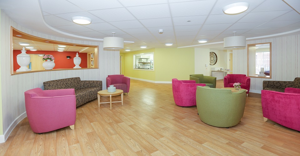 Communal seating area with tub chairs in pink and green at Whiston Court