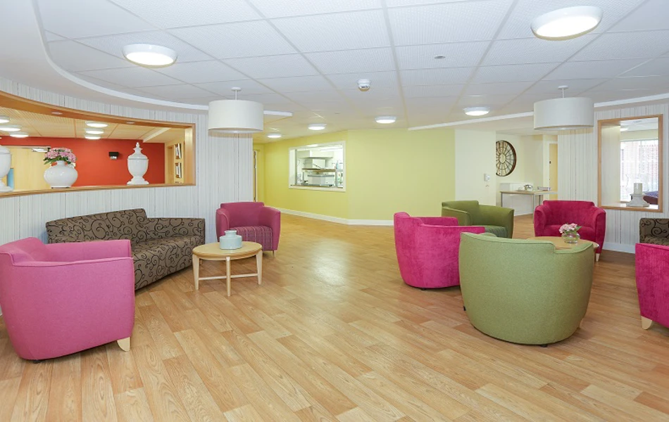 Communal seating area with tub chairs in pink and green at Whiston Court