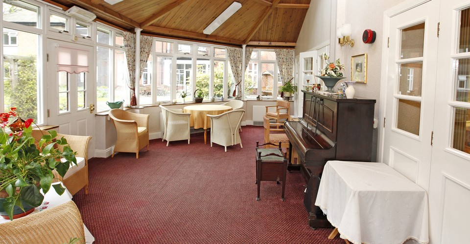 Large bright conservatory area with tables and a piano