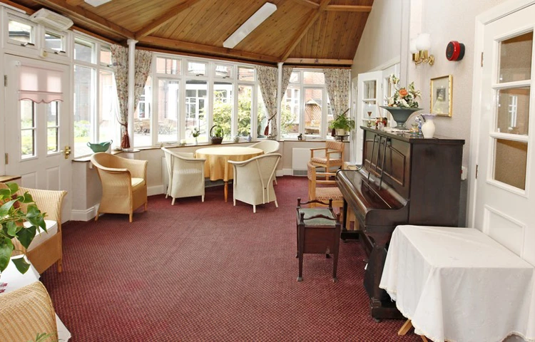 Large bright conservatory area with tables and a piano