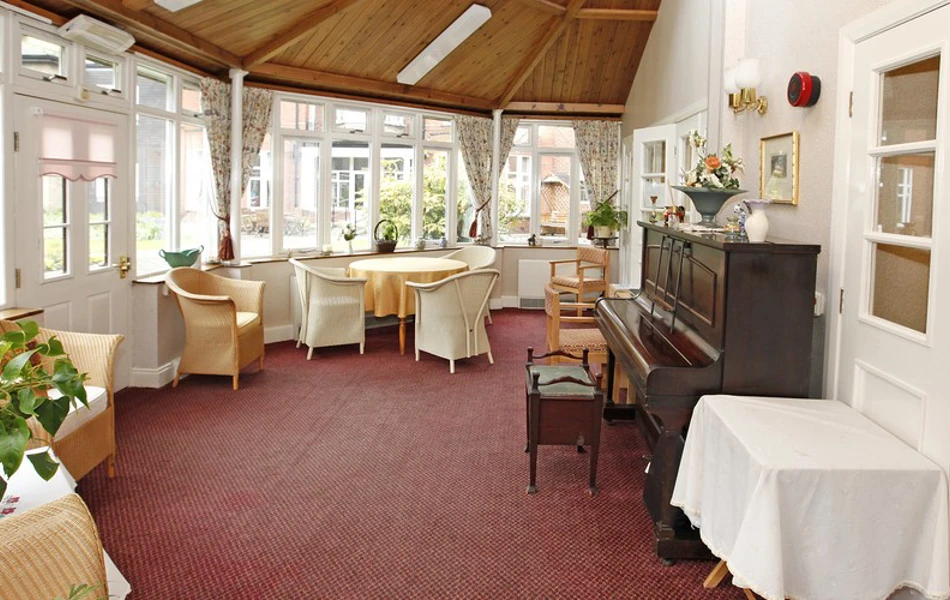 Large bright conservatory area with tables and a piano