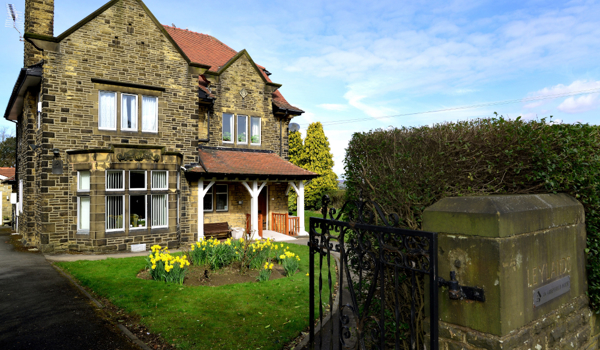 The front of a grand stone house with a porch