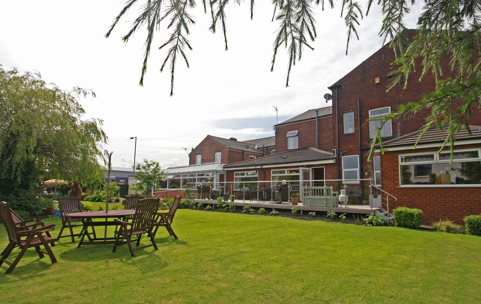 A view of the rear of the house with garden furniture on the grass