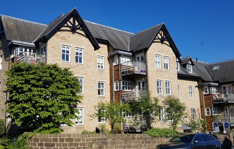 The outside of the house with blue skies surrounded by a stone wall