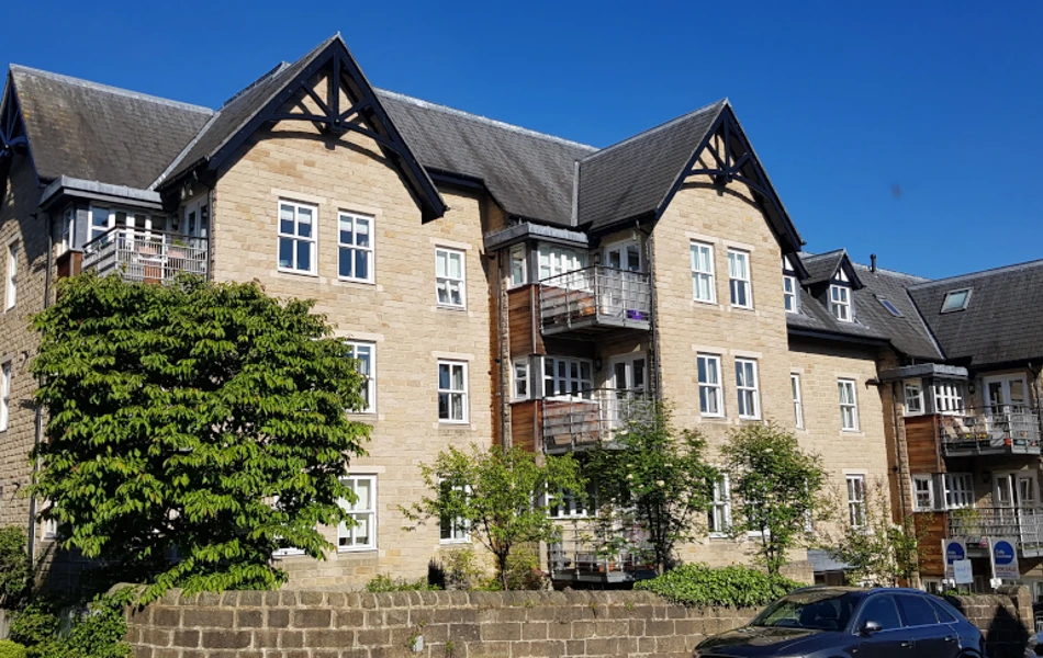The outside of the house with blue skies surrounded by a stone wall