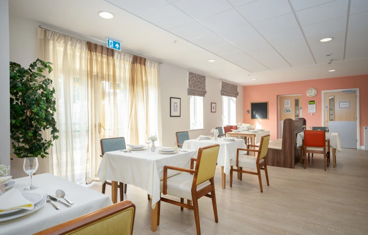 Resident dining room tables by windows at Hope Bank View