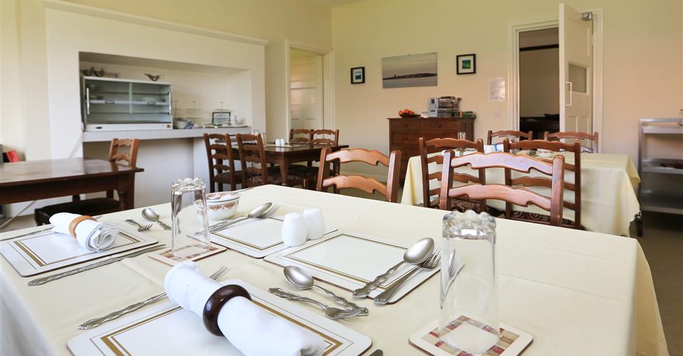 Dining area with tables set for dinner at Armstrong House