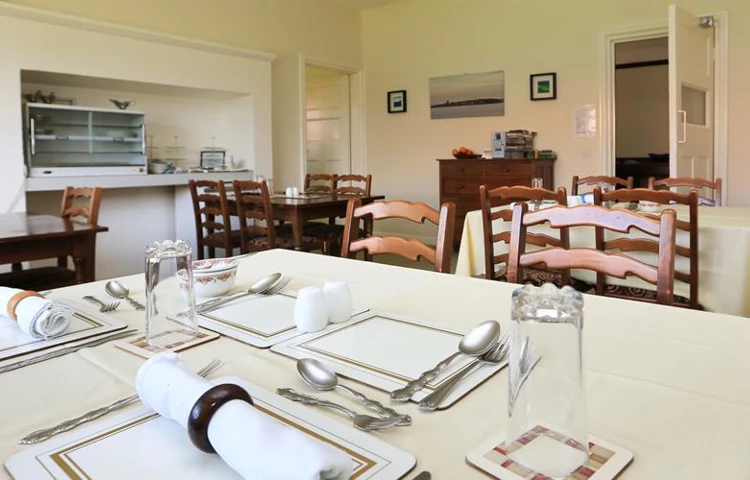 Dining area with tables set for dinner at Armstrong House