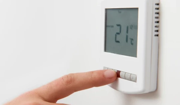 Person Adjusting Temperature On Thermostat