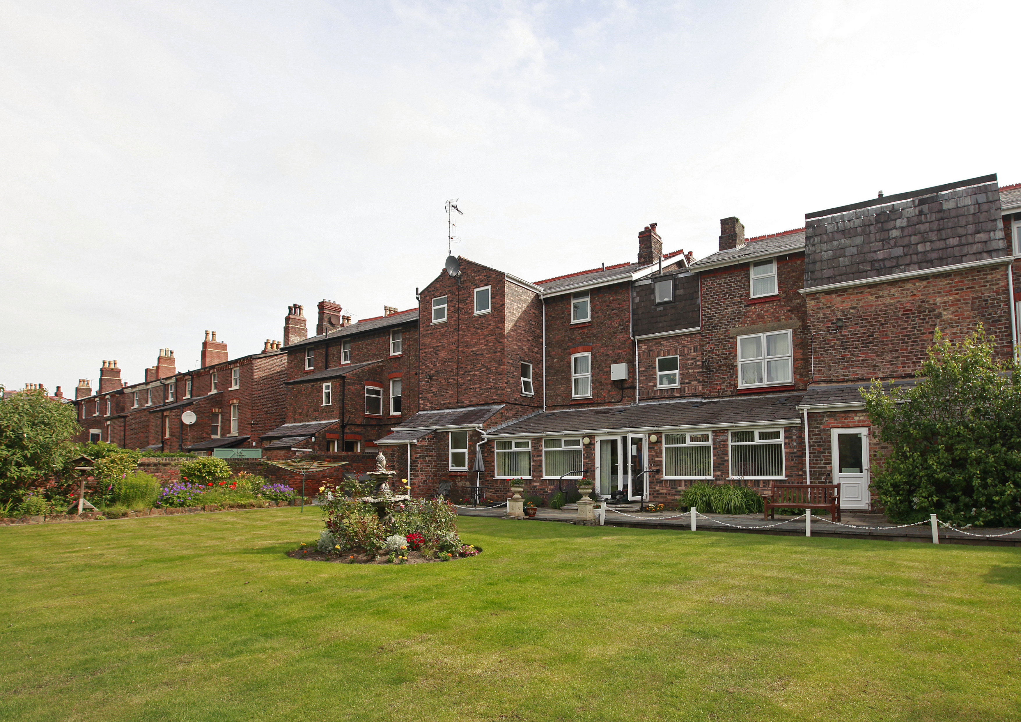 Large red brick house with garden and bird bath