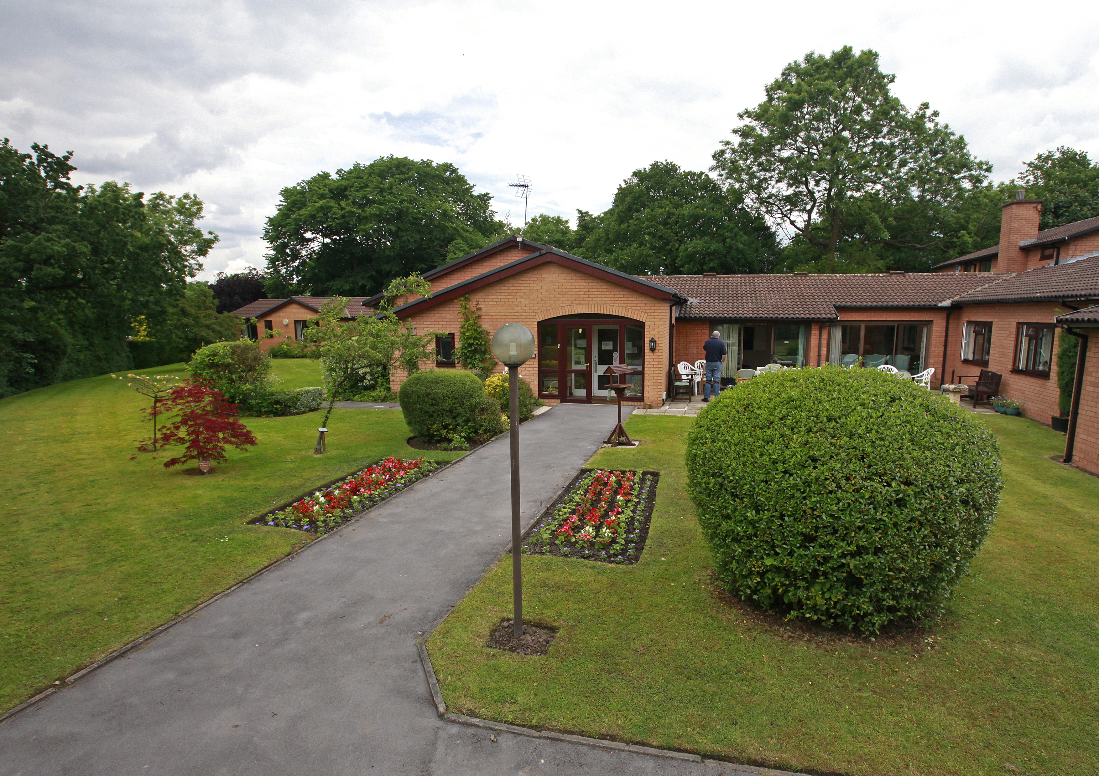 The path leading to the front entrance with tall lamps and flowers in the borders