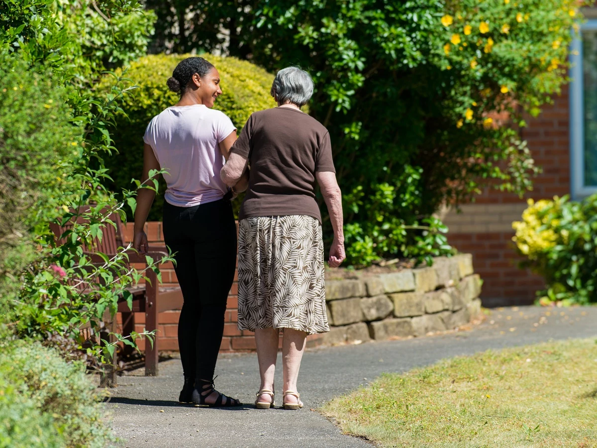 Staff Member And Resident Walking In The Garden