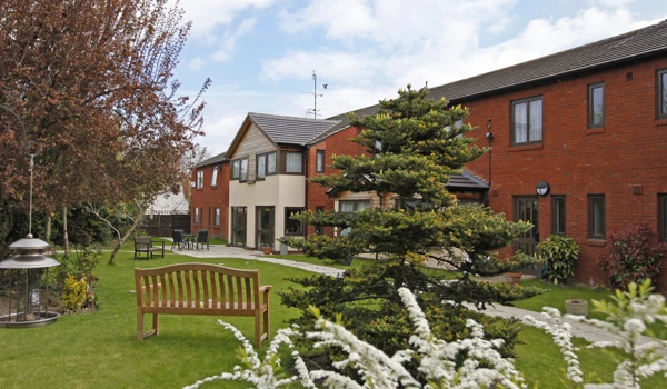 Beautiful garden at Abbeyfield House with bench and tables where residents can enjoy the sunshine