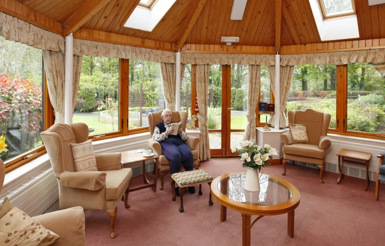 A resident sat reading in the conservatory