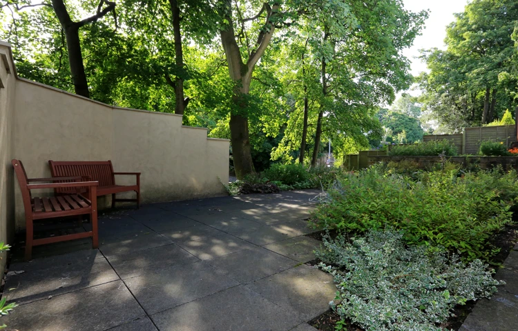The garden sheltered with trees and two park benches