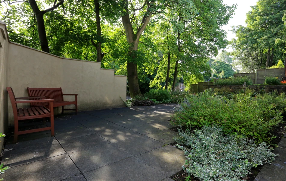 The garden sheltered with trees and two park benches