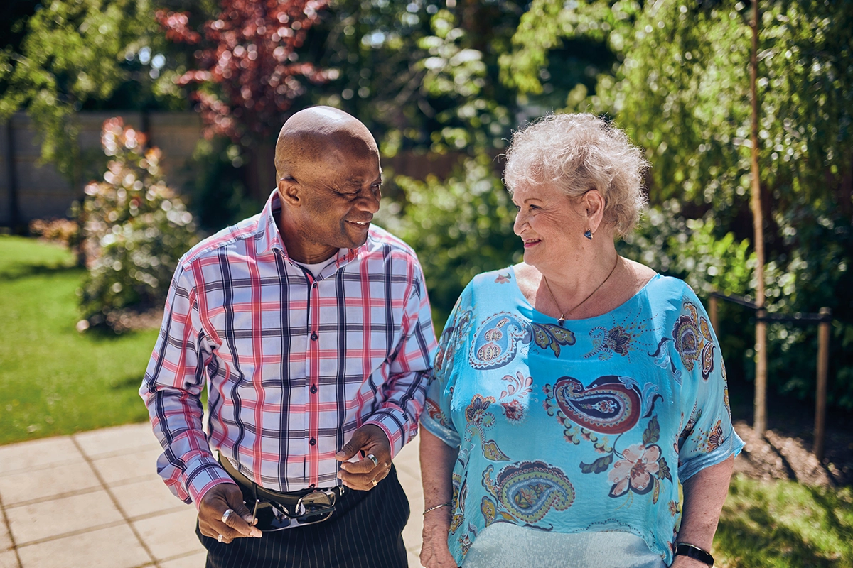 Older Man And Woman Walking Together In Bright Sunny Garden