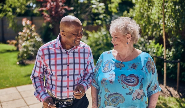 Older Man And Woman Walking Together In Bright Sunny Garden