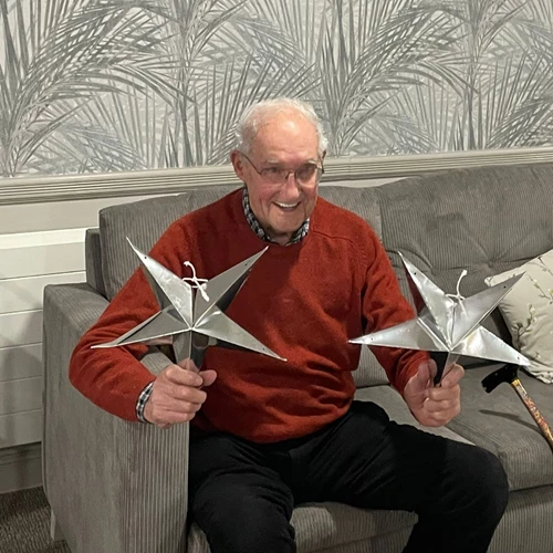 An older man holding two metal stars