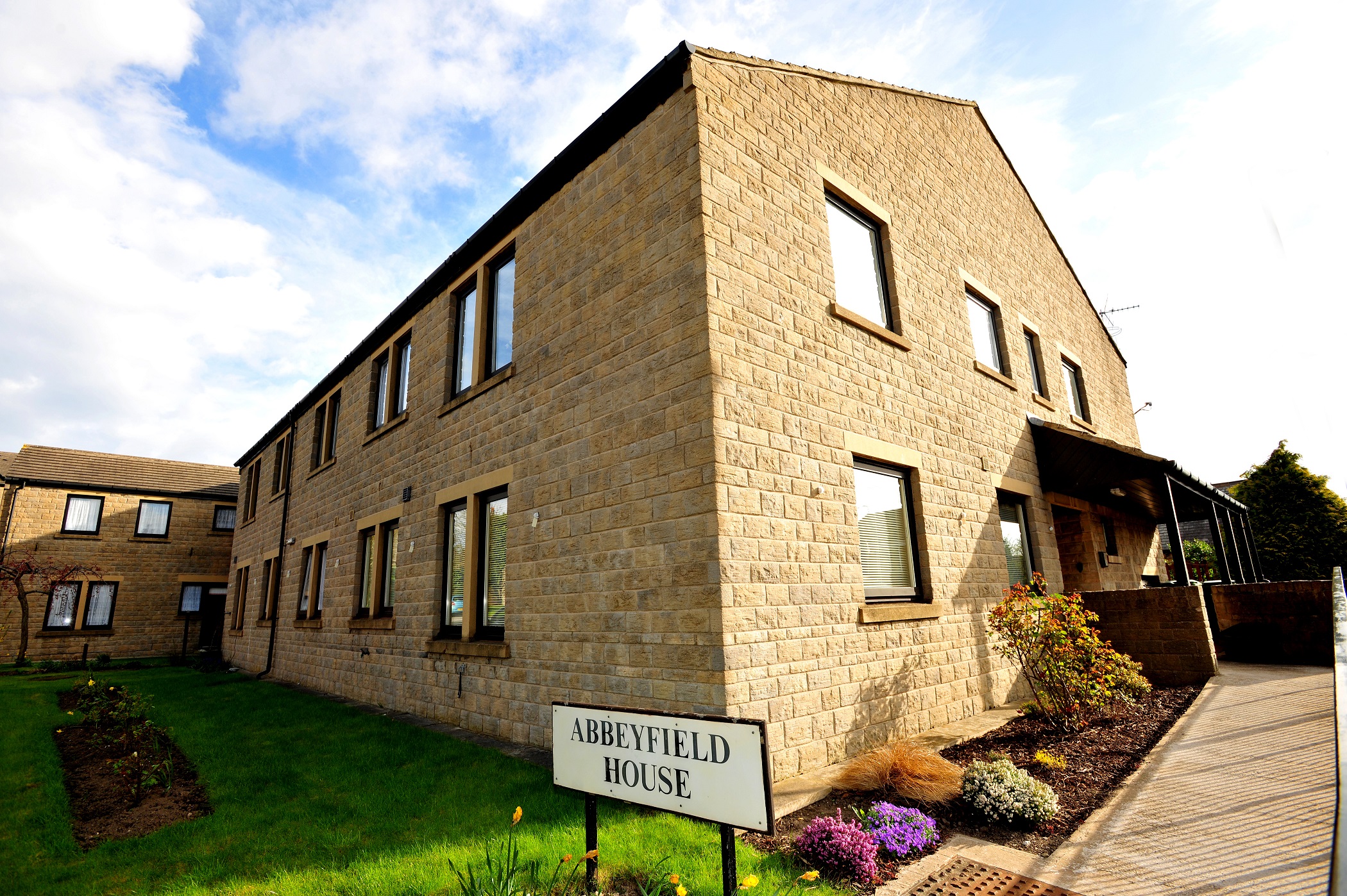 View of the outside of Abbeyfield House with gardens and shrubs